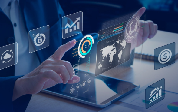 A person interacts with a futuristic digital interface displaying various icons, including graphs and a world map, above a tablet on a desk.